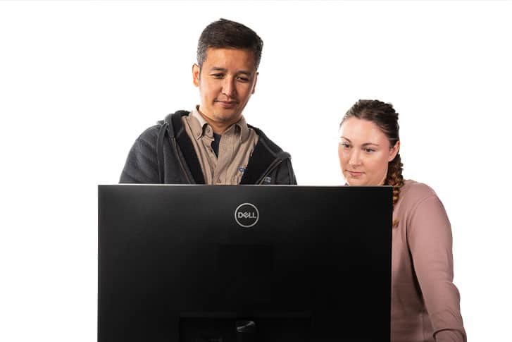 Two persons analyzing information on a computer screen, demonstrating teamwork and concentration.