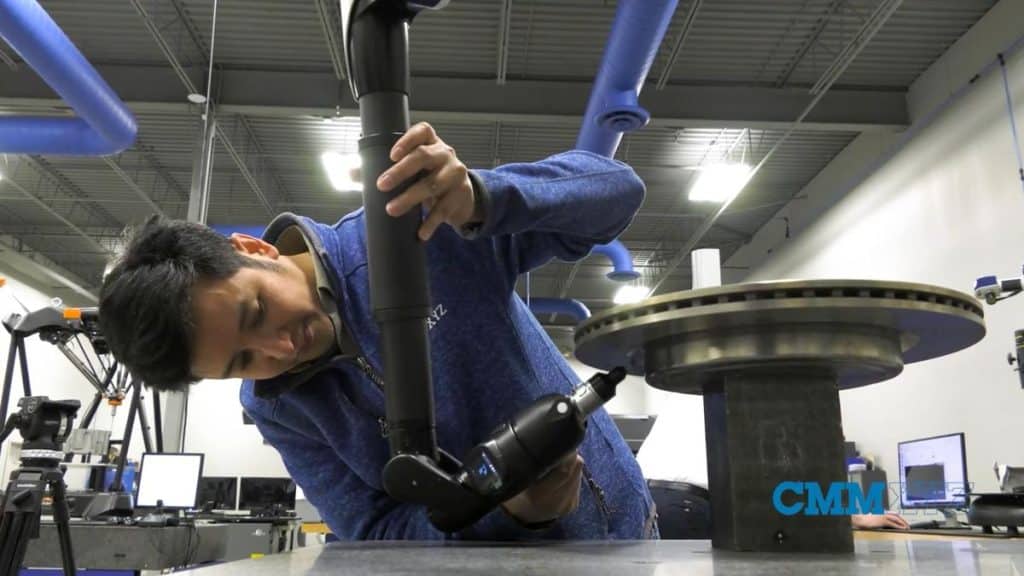 Technician performing CMM calibration and precision measurement using a coordinate measuring machine in an industrial metrology environment.